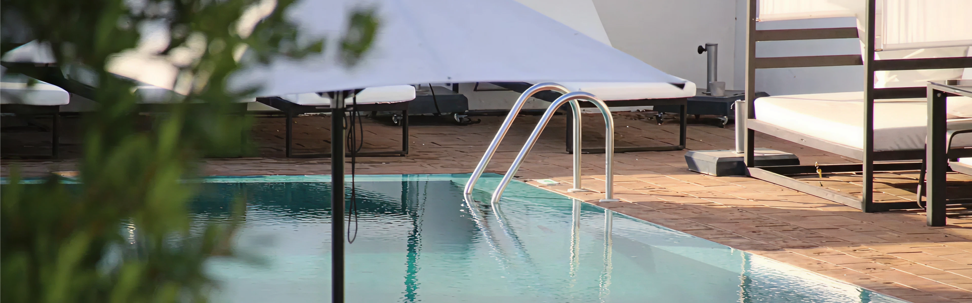 Sun loungers and a ladder beside a heated swimming pool on a timber deck